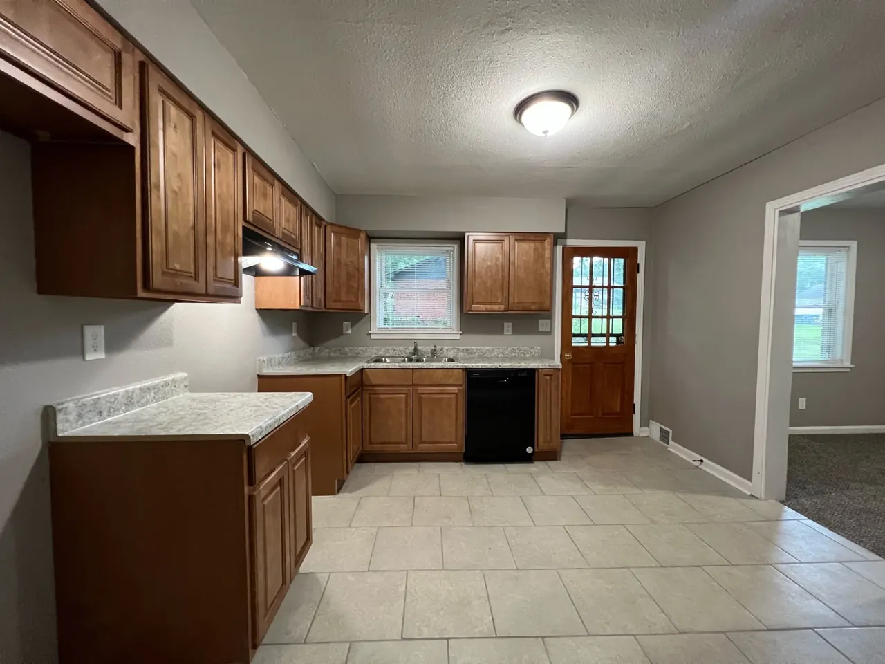 A renovated kitchen with wood cabinets, new counters, and tile floors
