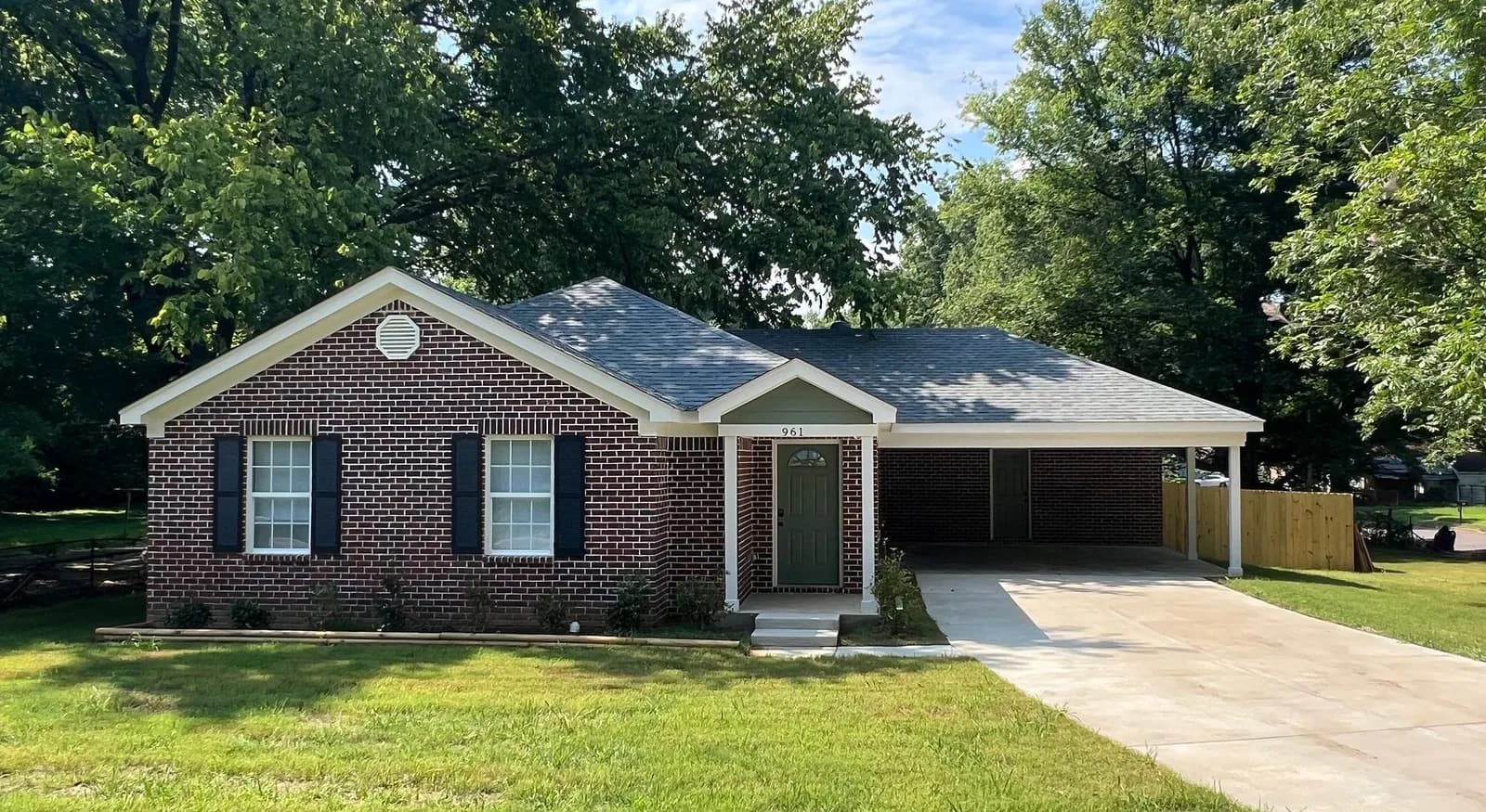 A newly built brick rental home in Memphis with a carport and fresh lawn